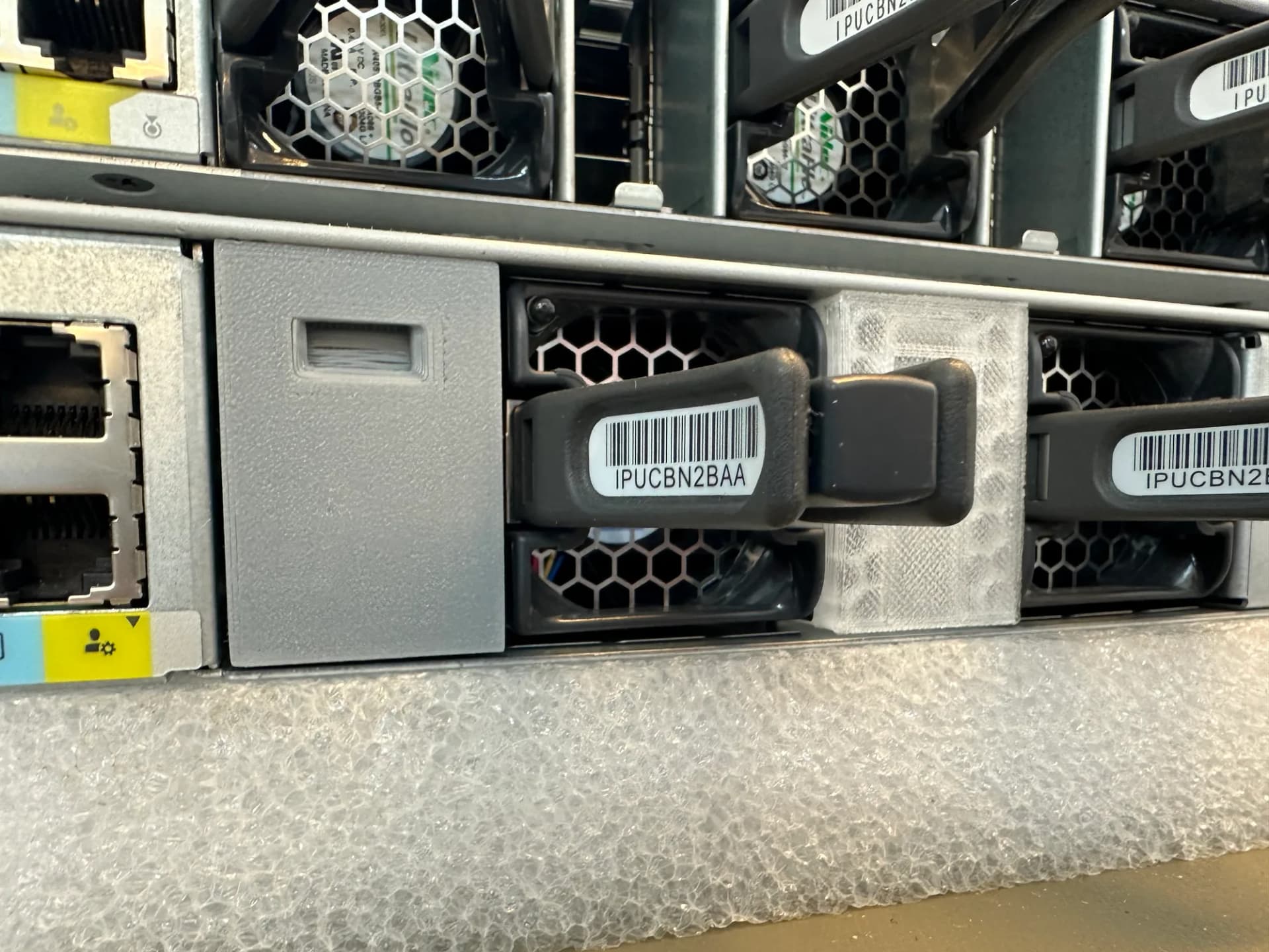 Rückseite eines Netzwerk-Switches mit eingesetzter 3D-gedruckter grauer Blende zwischen den Lüftermodulen